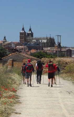 Five pilgrims on Camino Francés route of the Camino de Santiago with the Astorga Cathedral in the background