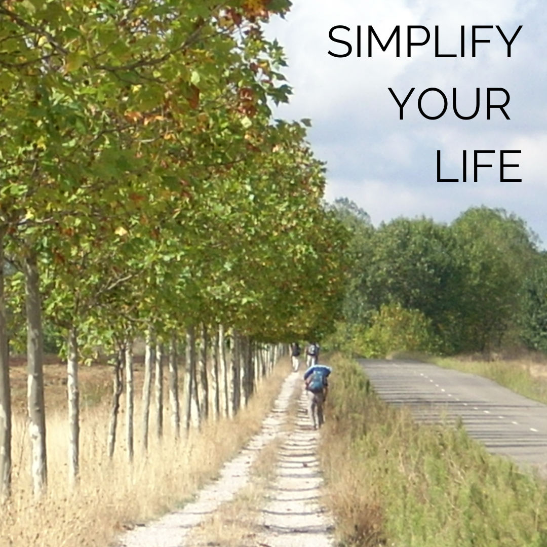 Photo of a pilgrim walking on the Camino Frances route of the Camino de Santiago in Spain, with the words "simplify your life"
